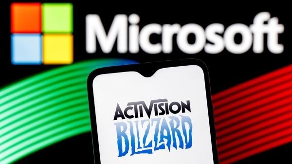 Handy mit Logo von Activision Blizzard vor Microsoft-Logo